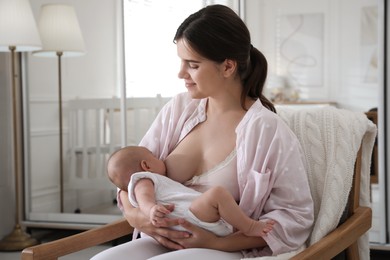 Photo of Young woman breastfeeding her little baby at home