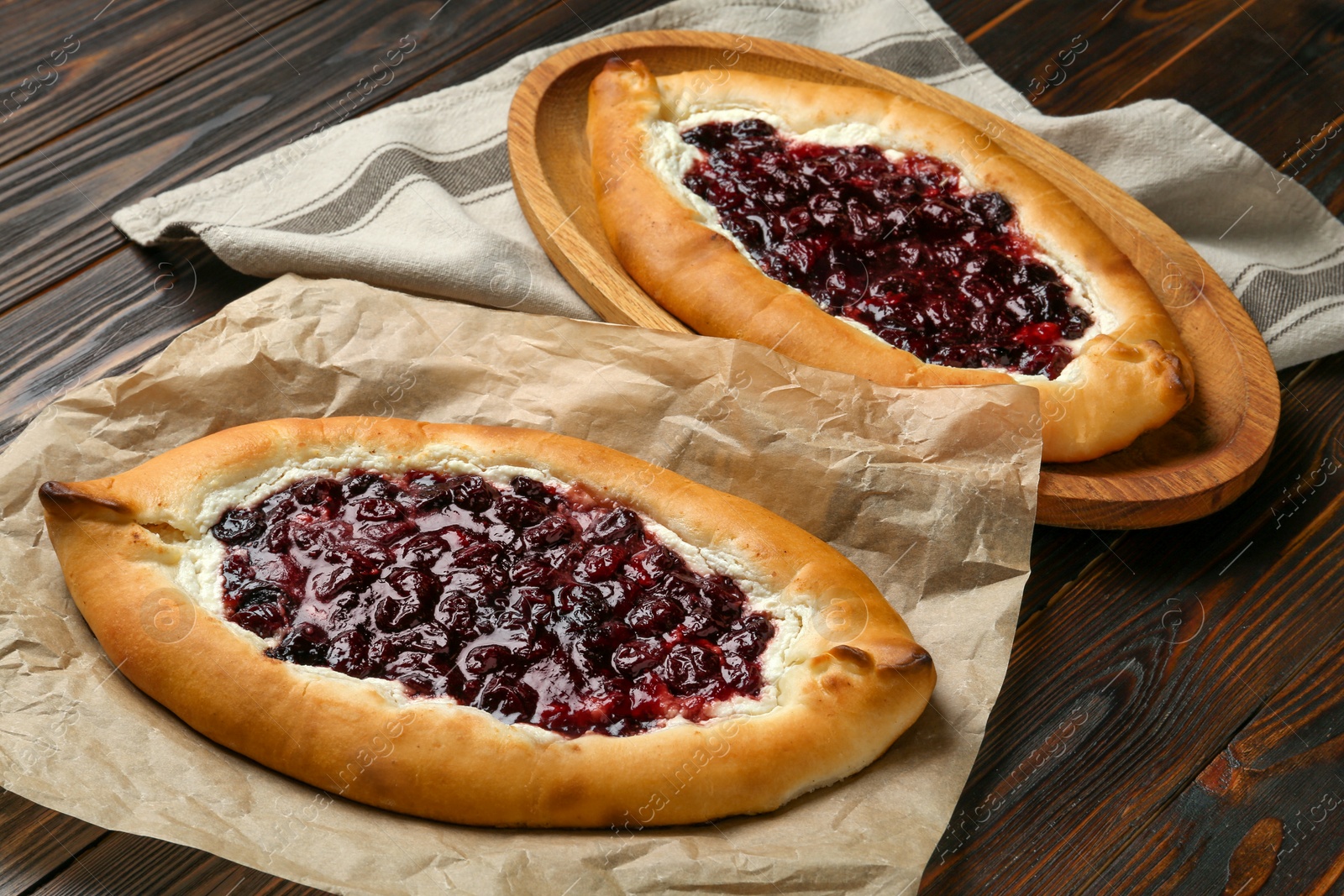 Photo of Delicious sweet cottage cheese pastries with cherry jam on wooden table