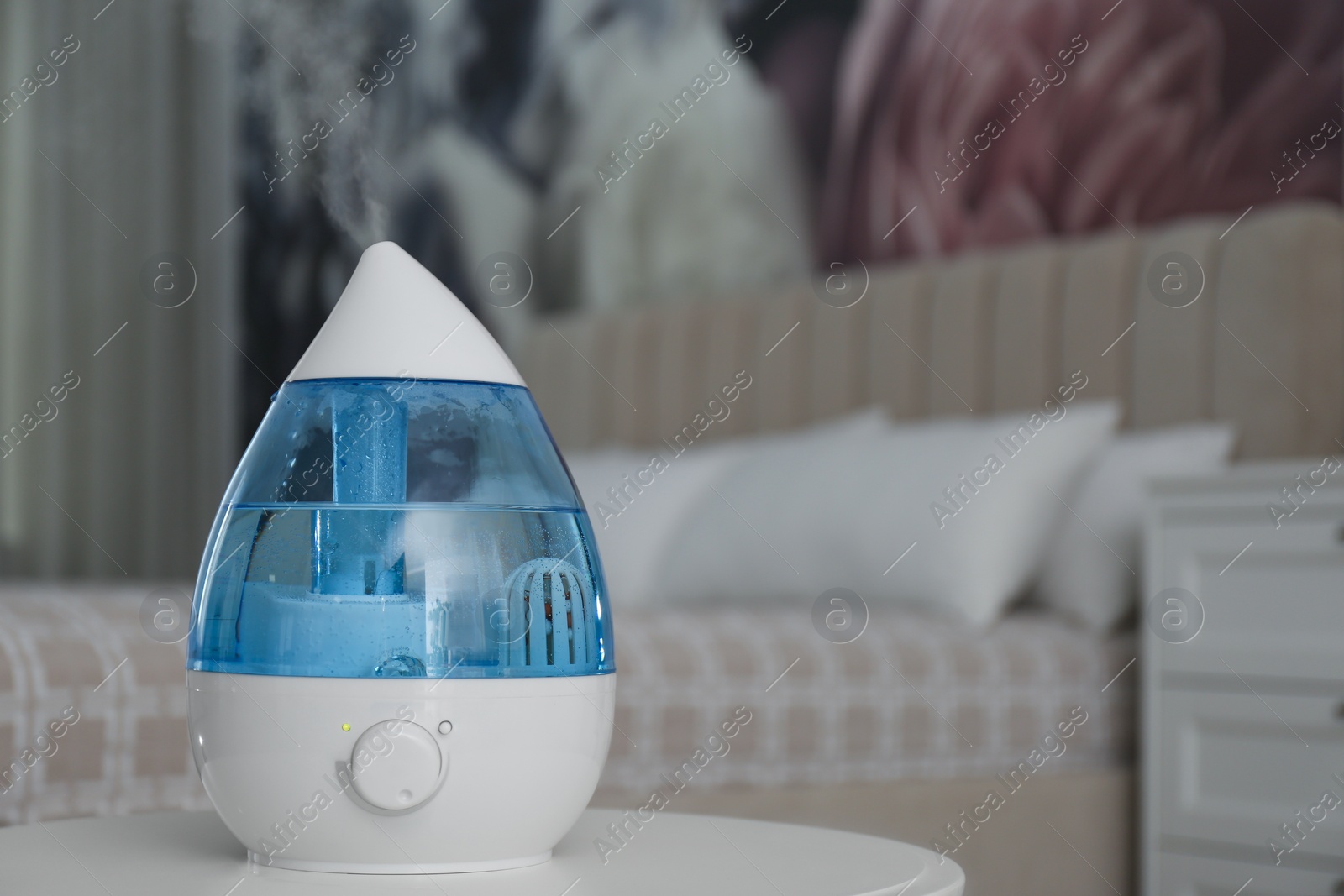 Photo of Modern air humidifier on table indoors. Space for text