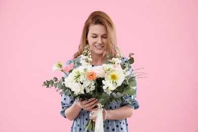 Beautiful woman with bouquet of flowers on pink background