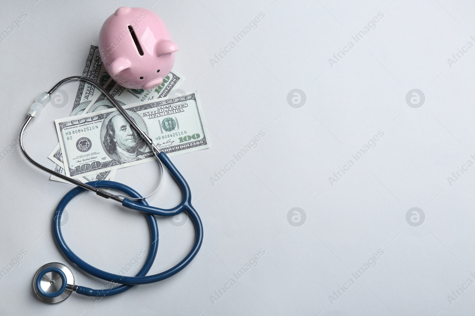 Photo of Stethoscope, piggybank and money on white background, top view. Health insurance concept