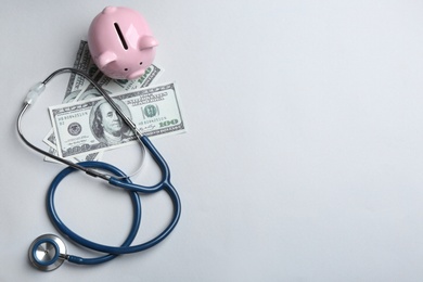 Stethoscope, piggybank and money on white background, top view. Health insurance concept