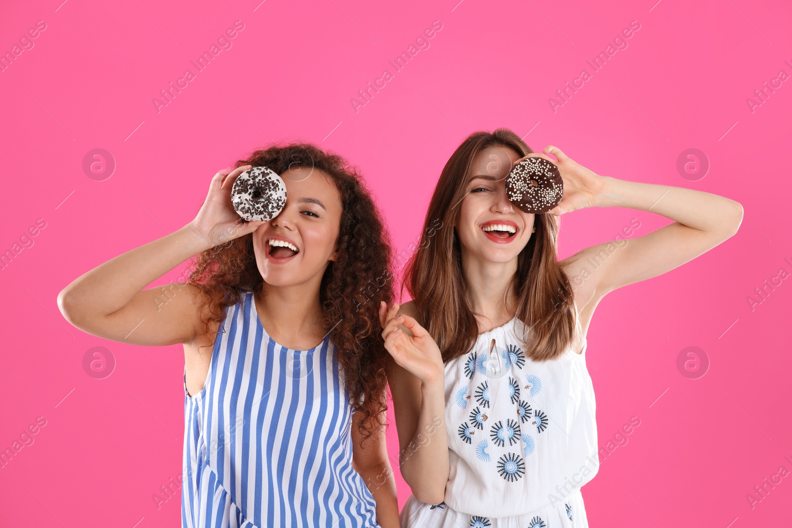 Photo of Beautiful young women with donuts on pink background