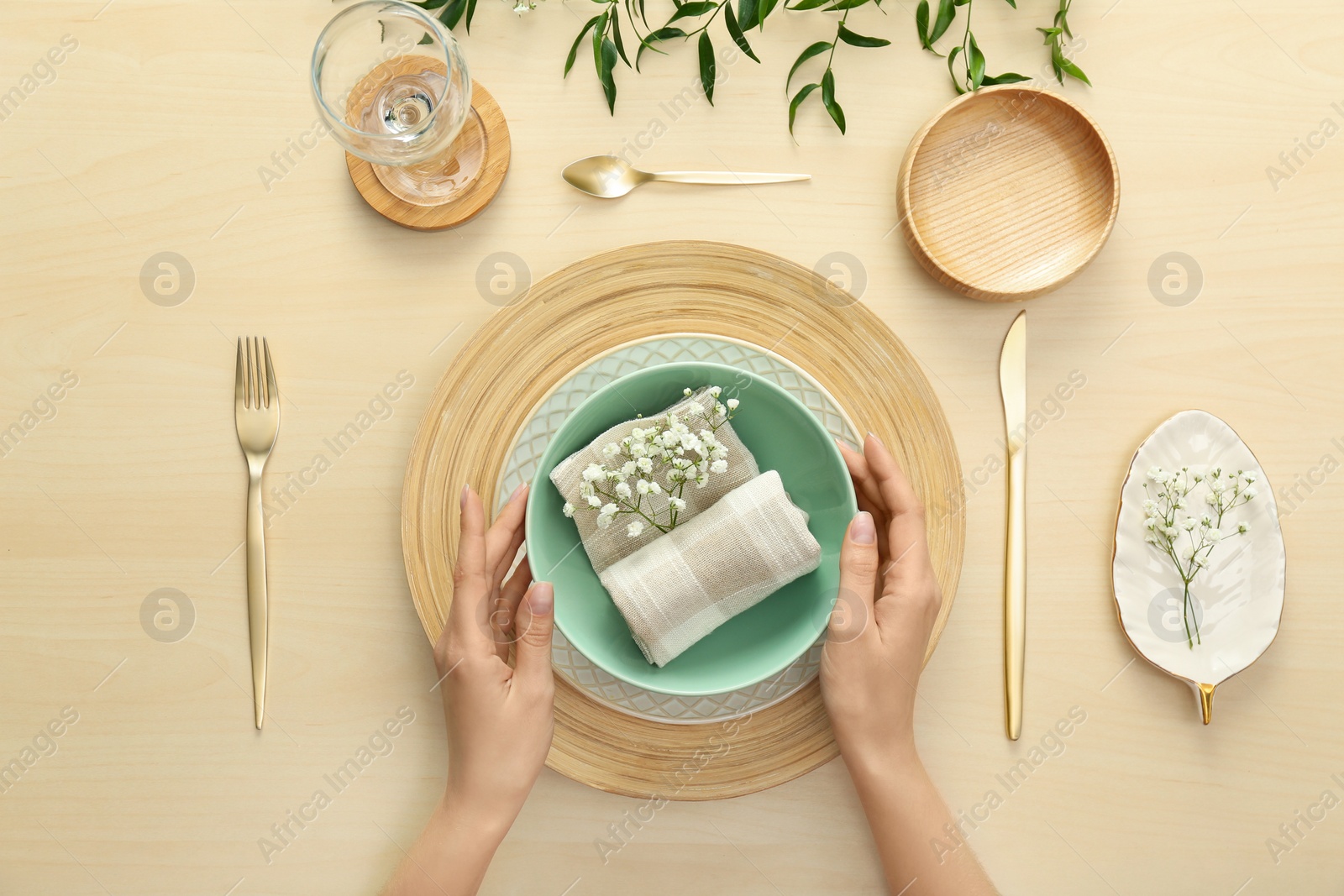 Photo of Woman setting table with flowers for festive dinner, top view