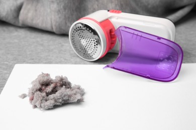 Photo of Modern fabric shaver and lint on light grey cloth