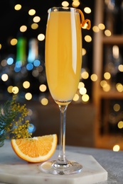 Mimosa cocktail with garnish and fresh fruit on bar counter against blurred lights