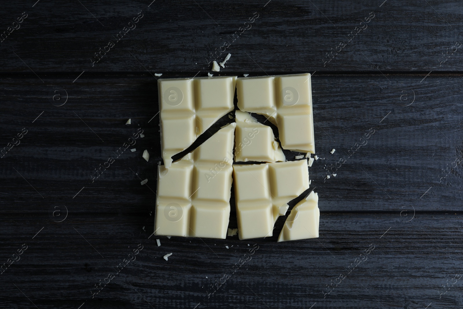 Photo of Delicious white chocolate on black wooden table, flat lay