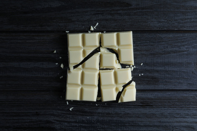 Delicious white chocolate on black wooden table, flat lay