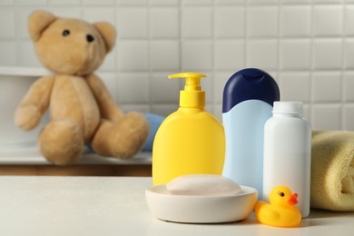 Baby cosmetic products, bath duck and towel on white table. Space for text