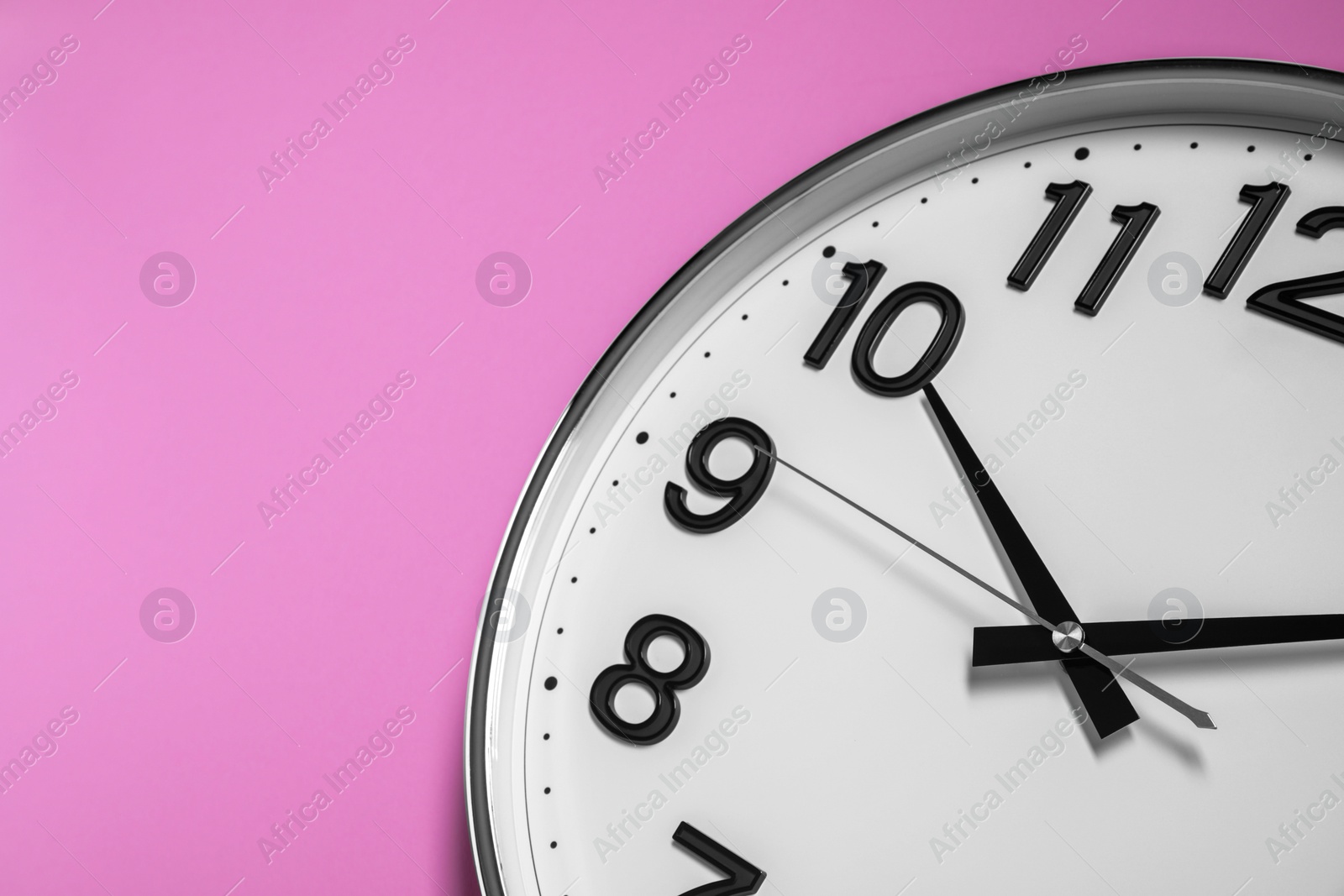 Photo of Stylish round clock on pale pink background, top view with space for text. Interior element