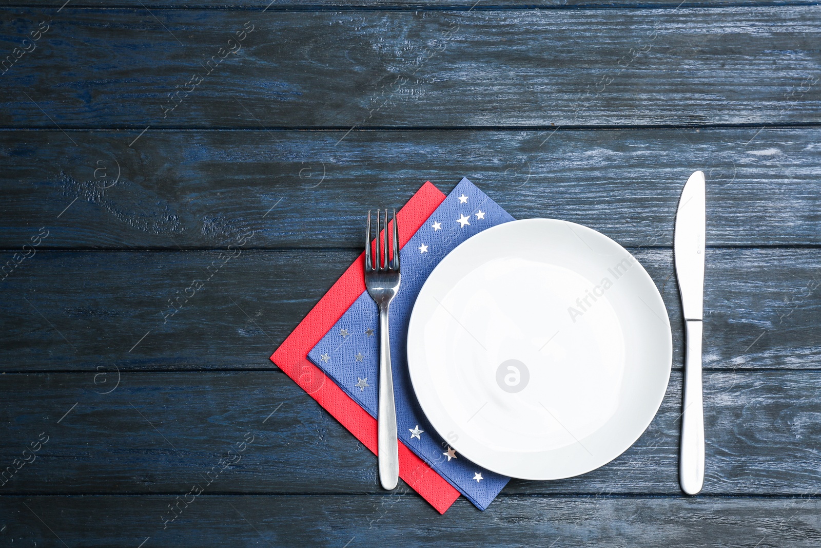 Photo of Patriotic table setting with traditional USA colors on wooden background, flat lay. Space for text