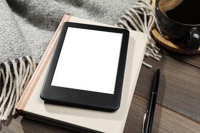 Photo of E-book reader with notebook and coffee on wooden table, closeup. Space for text