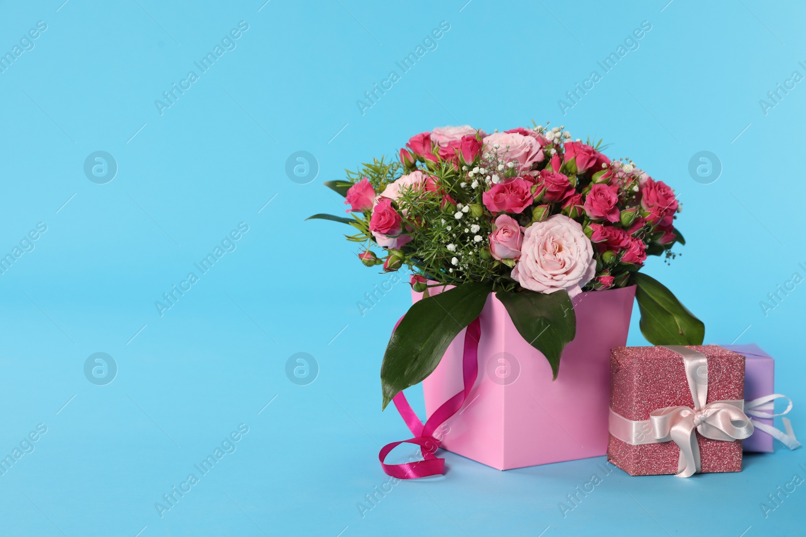 Photo of Beautiful bouquet of flowers and gift box on color background. Space for text