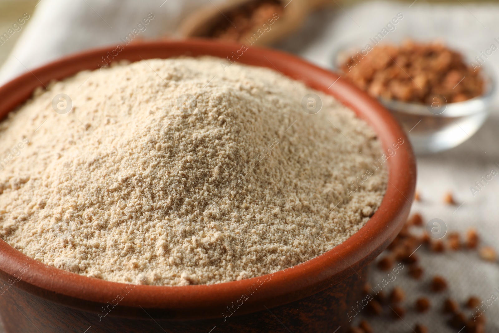 Photo of Bowl of buckwheat flour on cloth, closeup