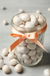 Photo of Glass jar with sweets on light grey table, closeup