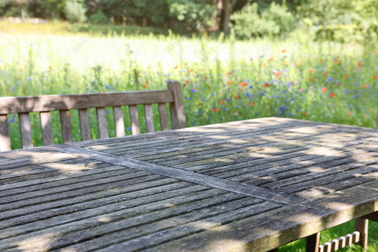 Photo of Empty wooden table with bench on sunny day in garden