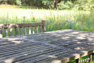 Photo of Empty wooden table with bench on sunny day in garden