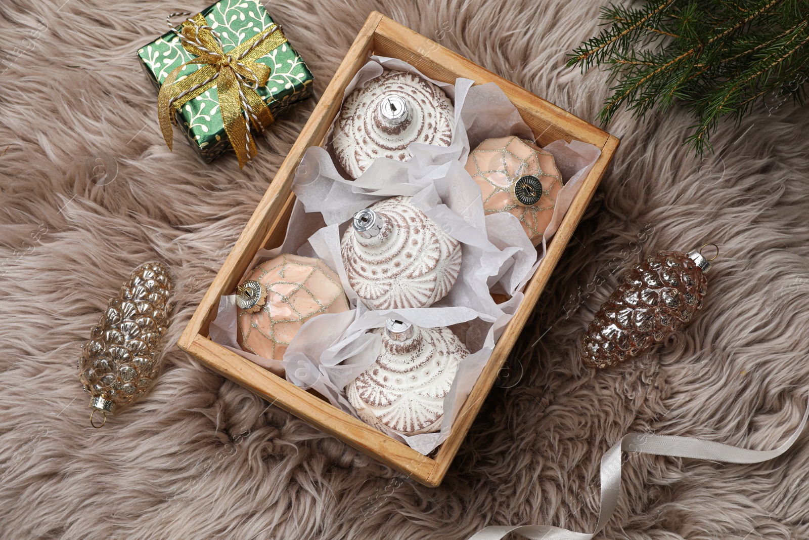Photo of Composition with beautiful Christmas baubles on beige fur, flat lay