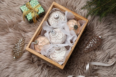 Composition with beautiful Christmas baubles on beige fur, flat lay