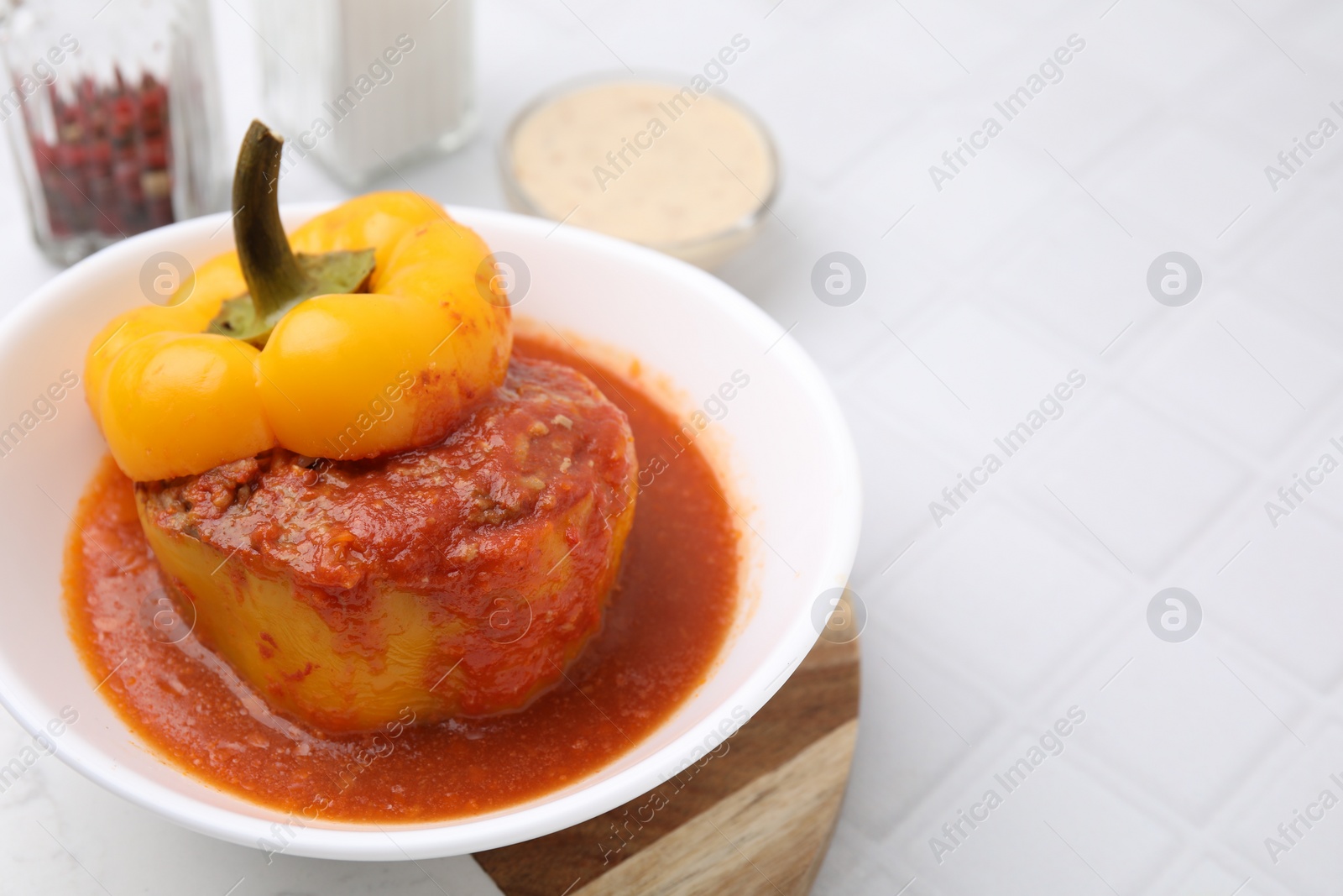 Photo of Delicious stuffed bell pepper served on white tiled table, closeup. Space for text