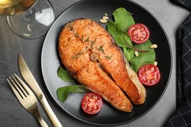 Delicious roasted fish served on grey table, flat lay