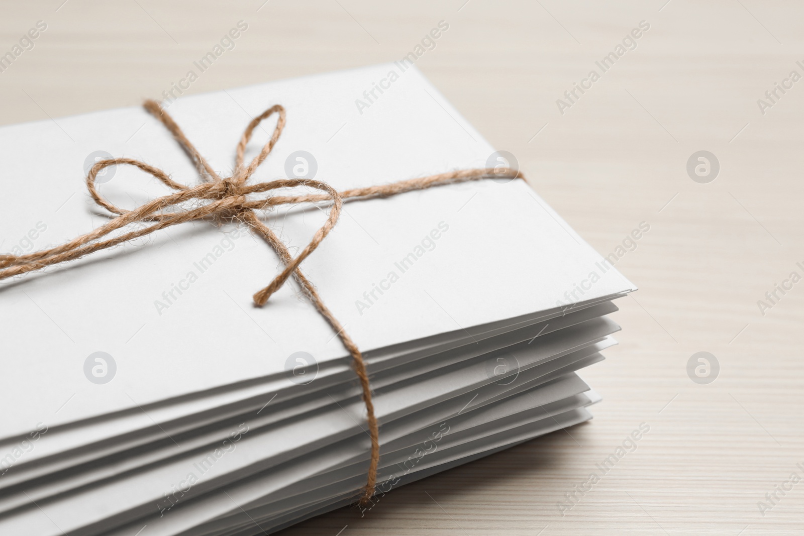 Photo of Stack of letters tied with twine on white wooden table, closeup