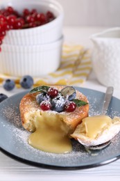 Photo of Tasty vanilla fondant with white chocolate and berries on light wooden table