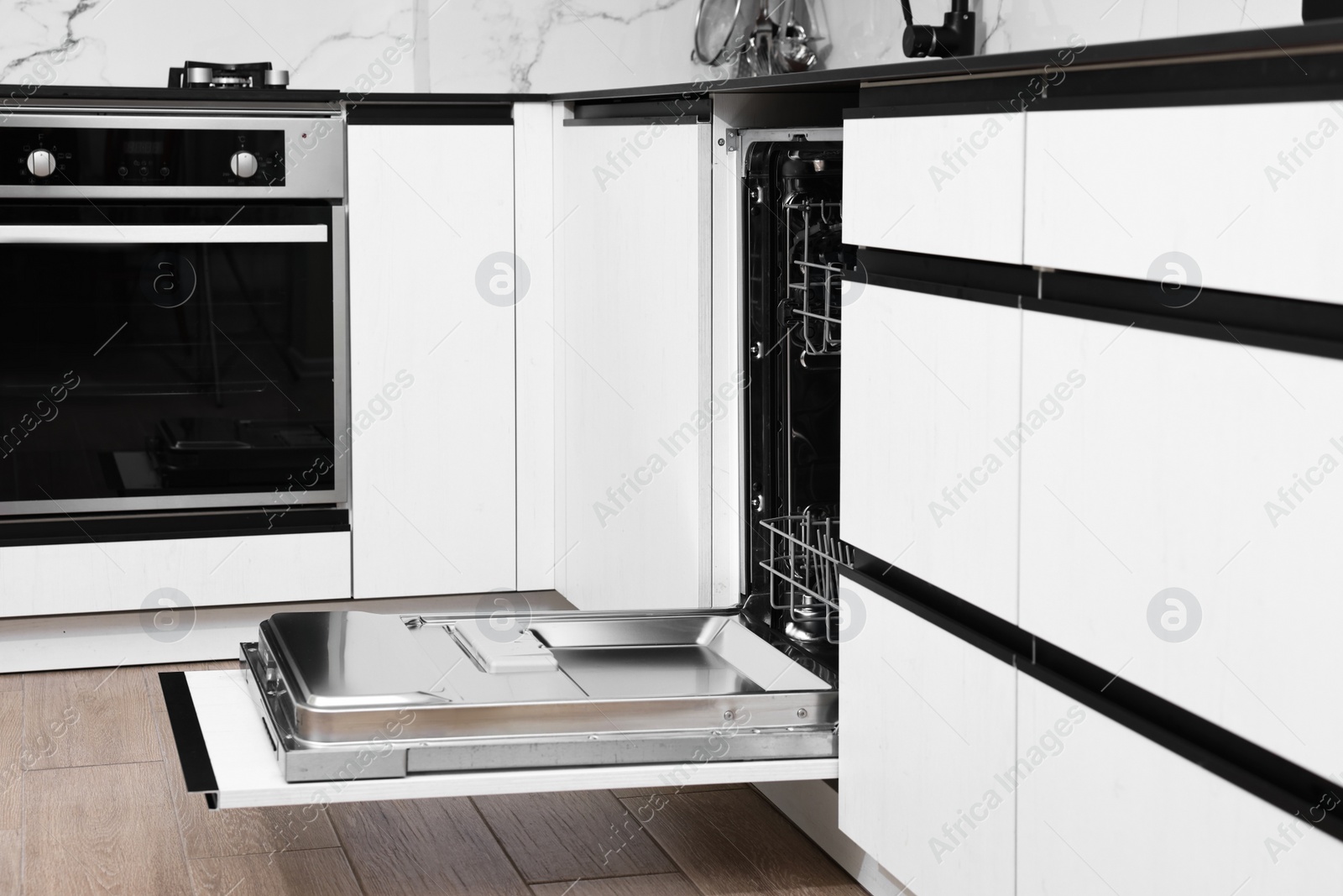 Photo of Open clean empty dishwasher in kitchen. Home appliance