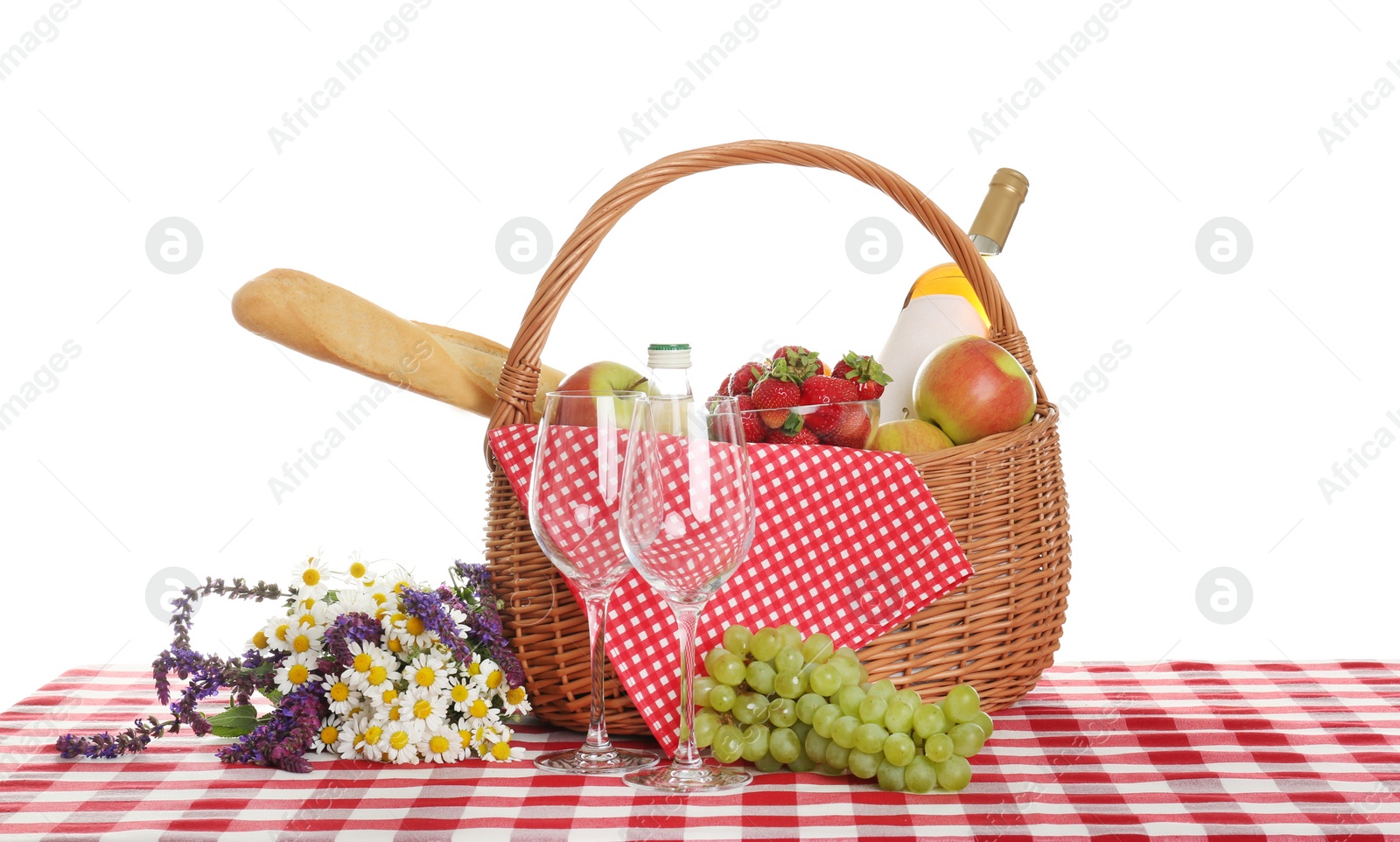 Photo of Picnic basket with wine and food on tablecloth against white background