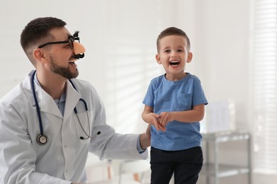 Pediatrician playing with little boy at hospital