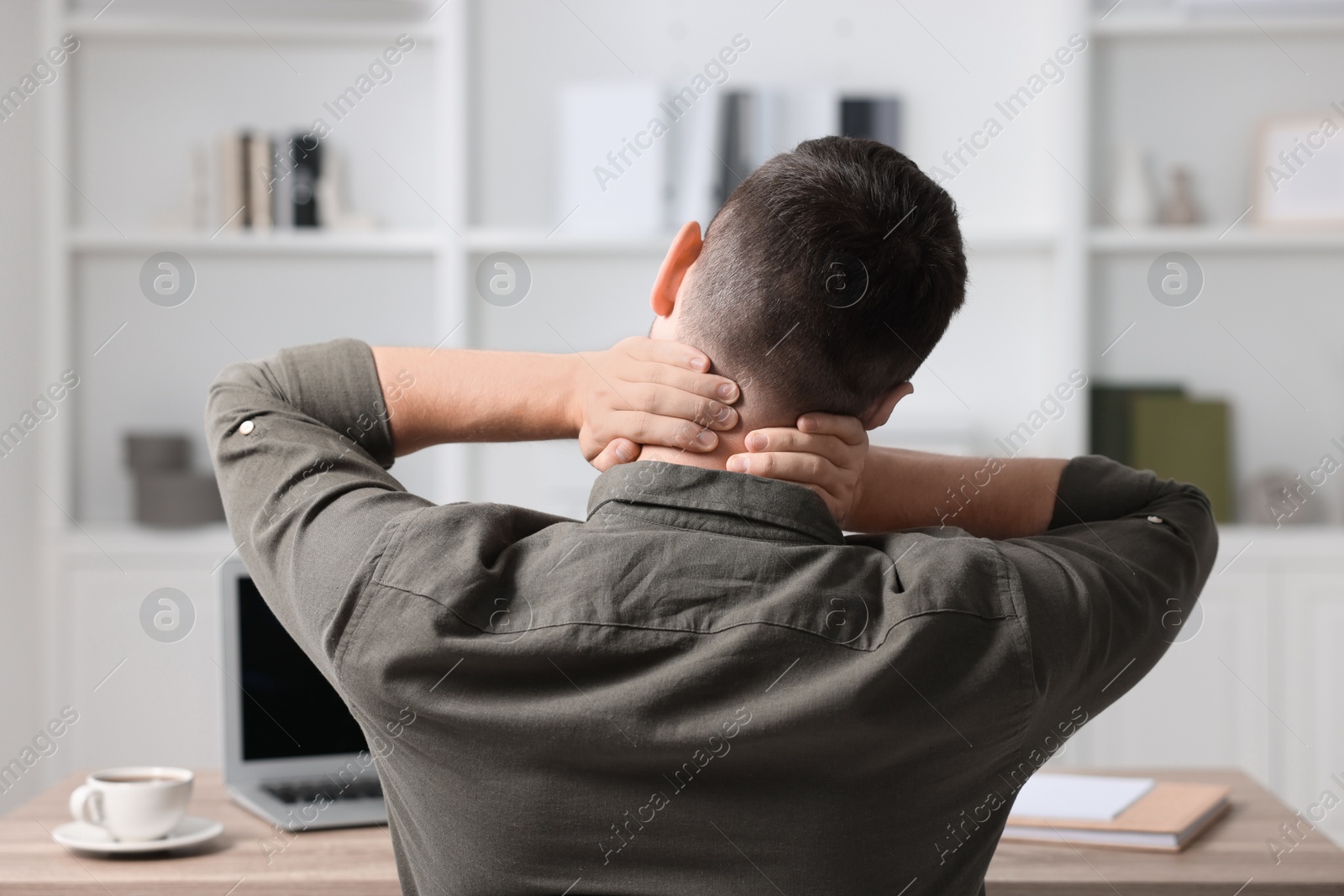 Photo of Man massaging stiff neck in office, back view