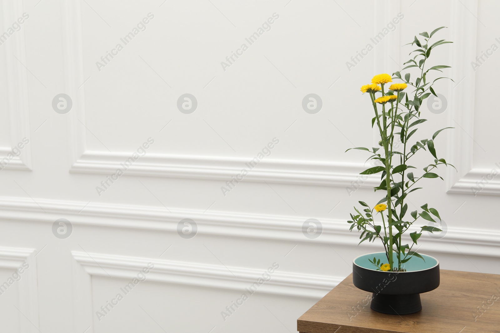 Photo of Ikebana art. Beautiful yellow flowers and green branch carrying cozy atmosphere at home, space for text