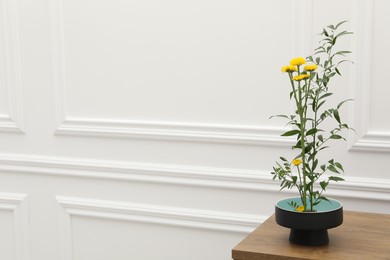 Photo of Ikebana art. Beautiful yellow flowers and green branch carrying cozy atmosphere at home, space for text