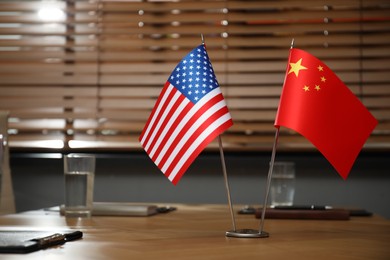 Photo of USA and China flags on wooden table in office. International relations
