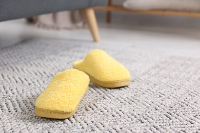 Photo of Yellow soft slippers on crochet carpet indoors, closeup