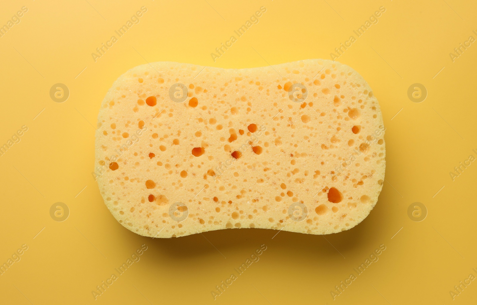 Photo of New sponge on yellow background, top view