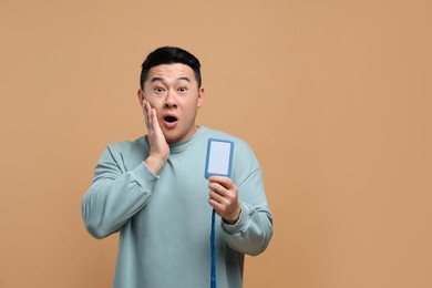 Photo of Emotional asian man with vip pass badge on beige background. Space for text