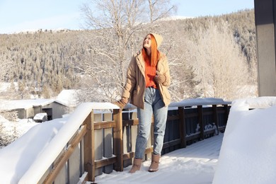 Photo of Happy young woman on terrace outdoors. Winter vacation