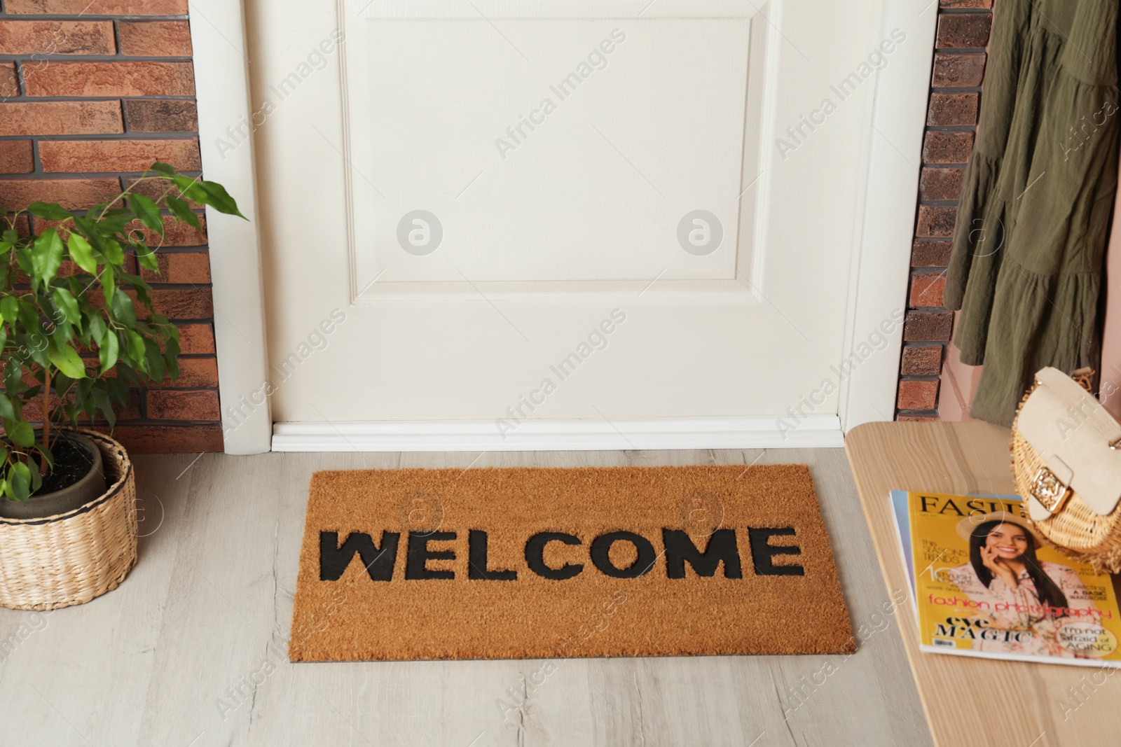 Photo of Door mat with word Welcome on wooden floor in hall