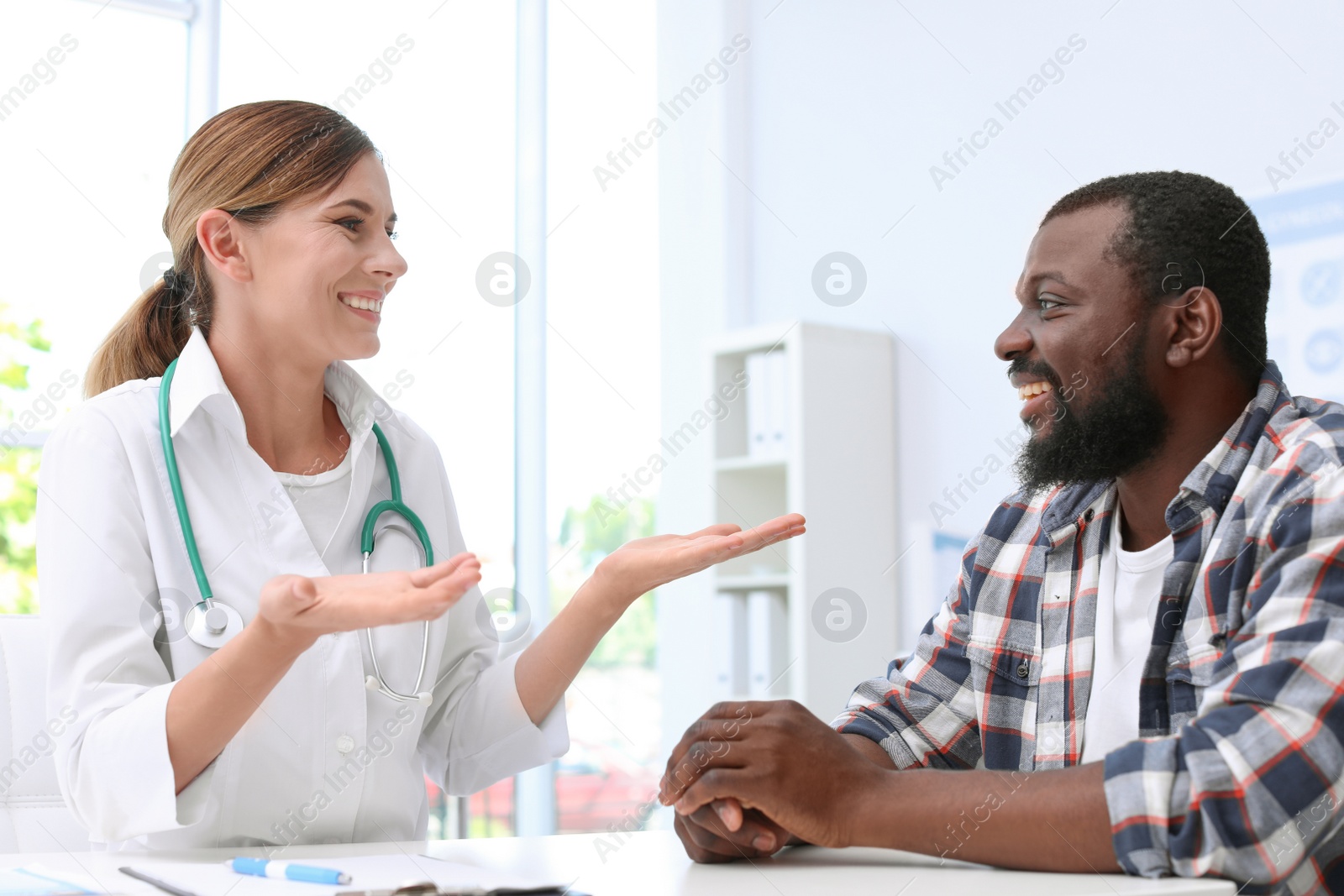 Photo of Young doctor speaking to African-American patient in hospital