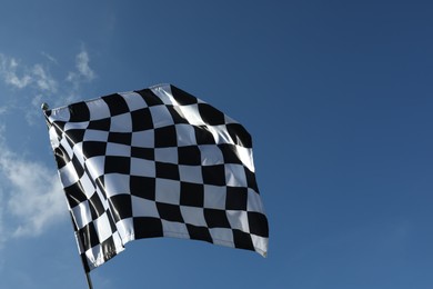 Photo of Checkered flag against blue sky outdoors, low angle view. Space for text