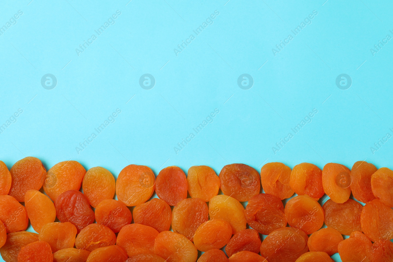 Photo of Dried apricots on color background, top view with space for text. Healthy fruit