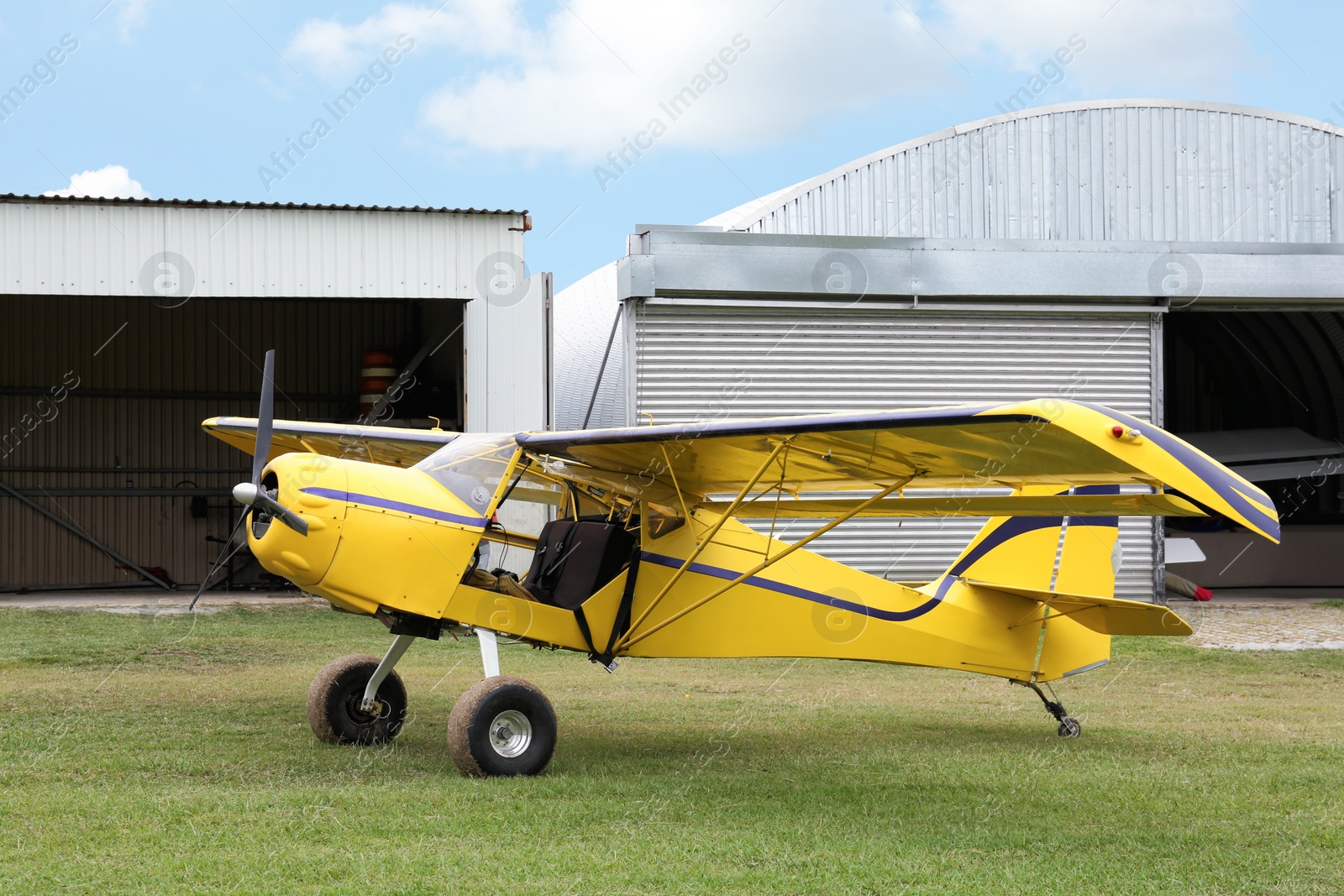 Photo of View of beautiful ultralight airplane near hangar in field