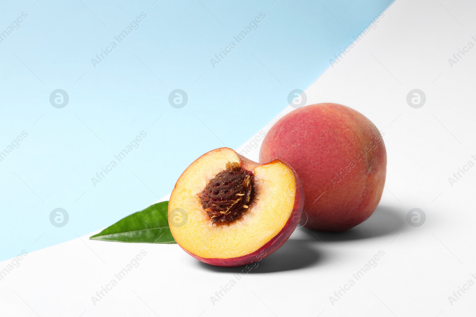 Photo of Delicious juicy peaches and leaf on color background