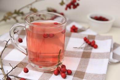 Cup with hawthorn tea and berries on table, closeup. Space for text