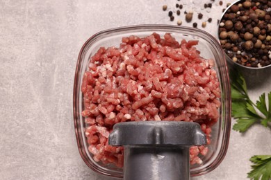Photo of Manual meat grinder with beef mince, peppercorns and parsley on light grey table, flat lay