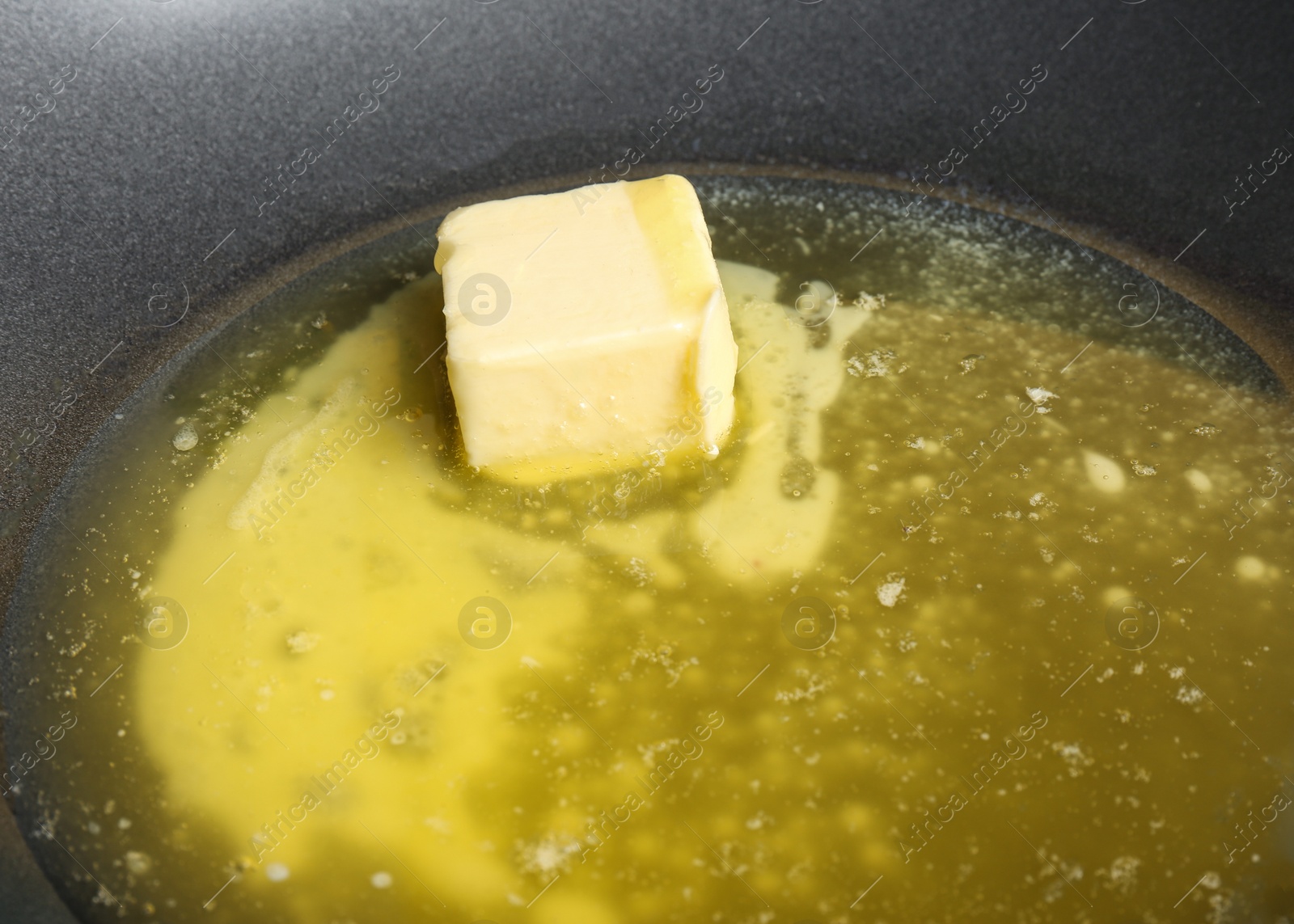 Photo of Piece of melting butter on frying pan, closeup