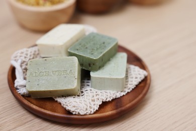 Photo of Tray with soap bars on light wooden table. Spa therapy