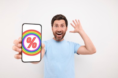 Image of Discount, offer, sale. Emotional man showing mobile phone with percent sign on screen, white background