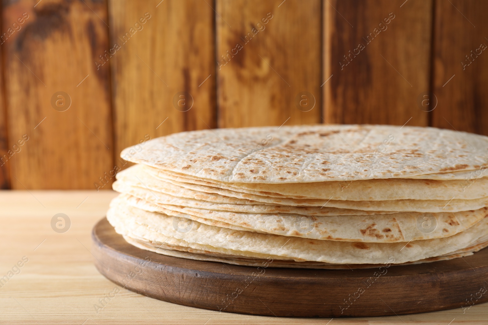 Photo of Many tasty homemade tortillas on wooden table, closeup